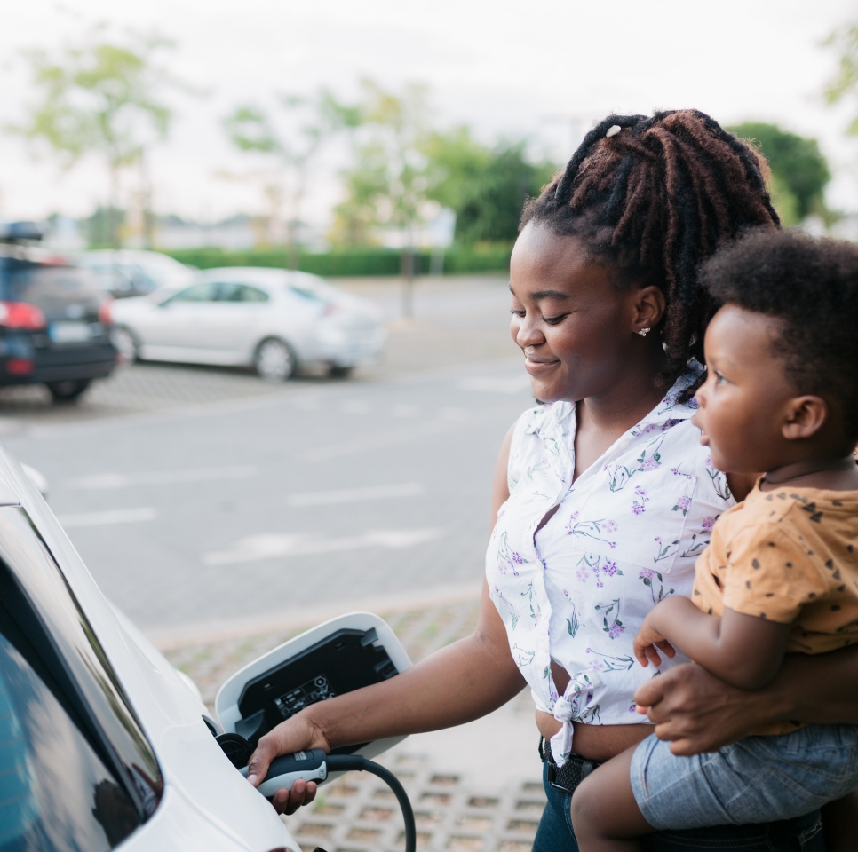 woman with child using EV charger